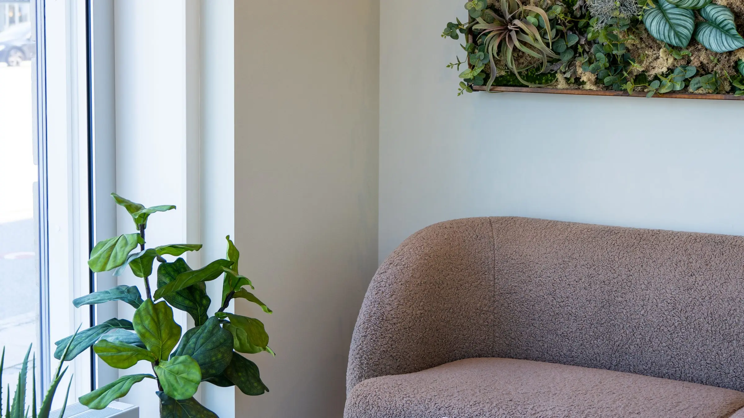 Cosmohagens venteområde med sofa, plantevæg og lys fra vinduet